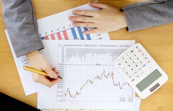 Businesswoman using calculator while analyzing graphs — Stock Photo, Image