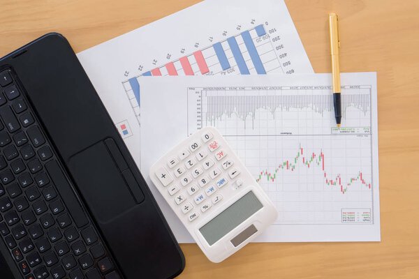 Various financial charts on the table with laptop, calculator an