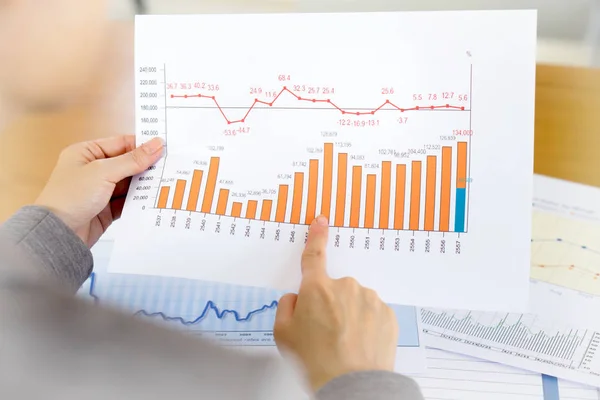 Podnikatelka ruce nad papír a finanční graf — Stock fotografie