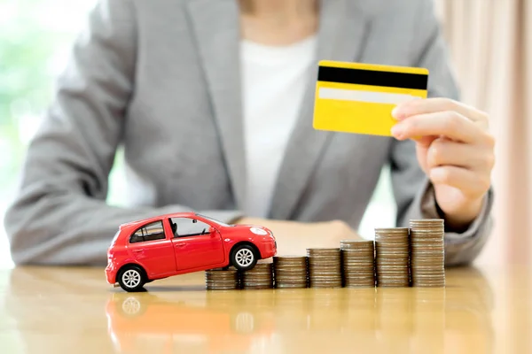 Zakenvrouw hand houden creditcard, een speelgoedauto en een stapel van co — Stockfoto