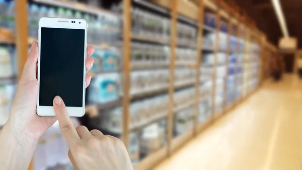 Frau benutzt Smartphone beim Einkaufen im Supermarkt — Stockfoto