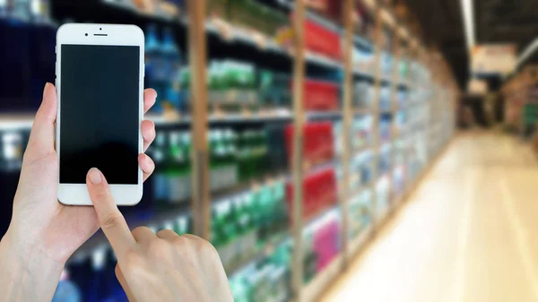 Frau benutzt Smartphone beim Einkaufen im Supermarkt — Stockfoto