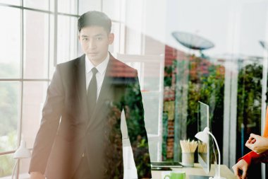A businessman  analysis document  seen through glass in new offi