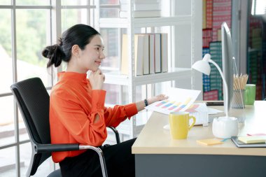 Ofiste çalışan kadın yönetmen masa başında oturmuş, otobüsü inceliyor.