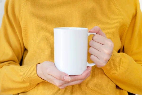 Sıcak kazaklı kadın elinde beyaz kupa tutuyor.