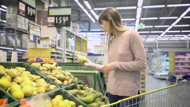 若い女性と話したスーパーで梨を選択します。 — ストック動画