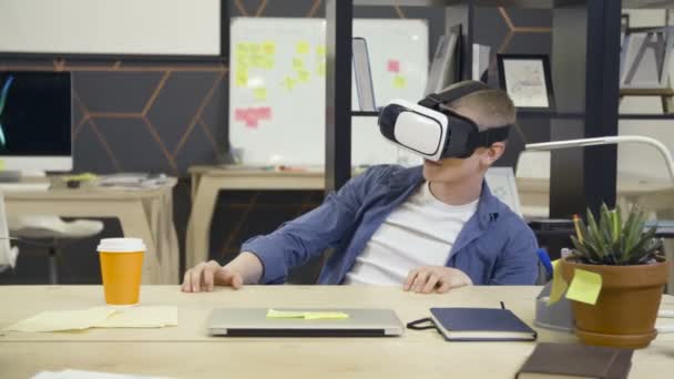 Joven utiliza gafas de realidad virtual en la oficina — Vídeos de Stock