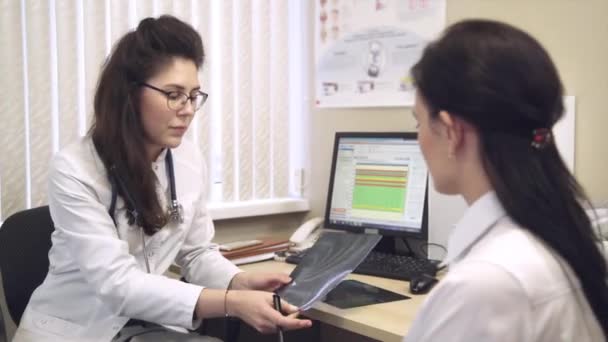 Lékař s pacientem mluví a ukazuje rentgen — Stock video