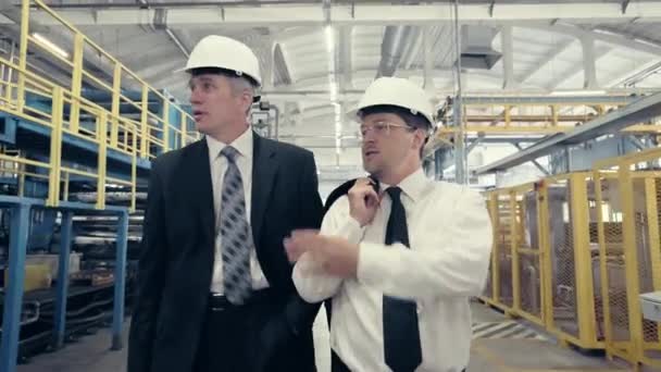 Des hommes d'affaires marchant à travers l'usine et parlant — Video