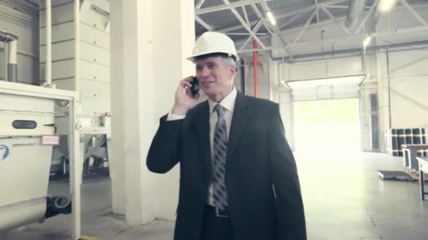 Hombre caminando por la fábrica y hablando por teléfono — Vídeo de stock