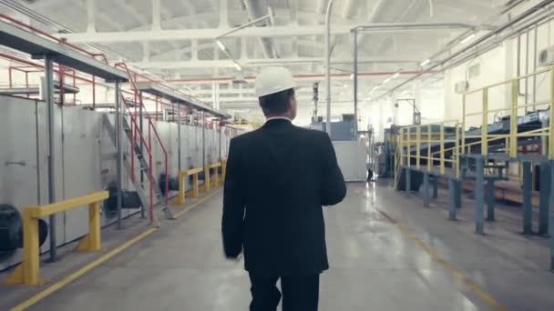 Achteraanzicht van zakenman wandelen door de fabriek — Stockvideo