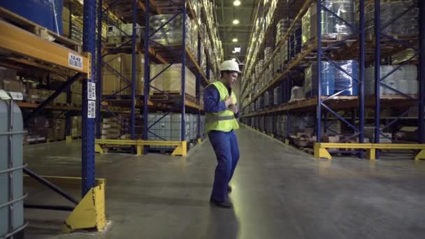 Werknemer dansen tussen rekken in magazijn — Stockvideo
