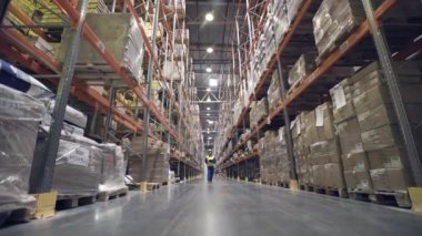 Depo işçisi ambar satırları arasında yürüyor