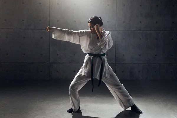 Женщина в кимоно практикует карате — стоковое фото