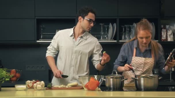 Молодая пара готовит на кухне — стоковое видео