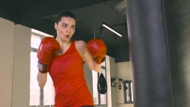 Молодая женщина бьет боксерскую сумку — стоковое видео