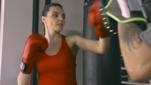 Жінка тренується з тренером в боксерському клубі — стокове відео