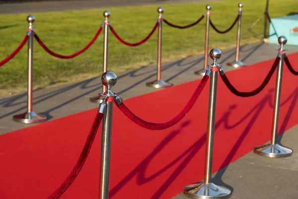 Langer roter Teppich zwischen Seilbarrieren am Vip-Eingang. — Stockfoto