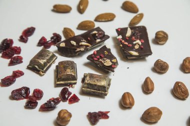 Siyah, kızılcık, fındık ve badem beyaz arka plan üzerinde çikolata parçalarını.