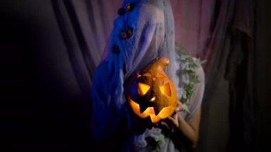 Cadılar Bayramı Cadısı, karanlık bir odada sihirli bir balkabağı. Cadılar şapka ve kostüm oyma balkabağı tutan güzel genç kadın.