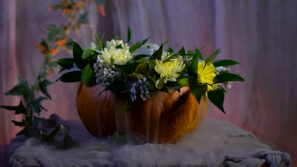 Хеллоуїн, наповнений святковими традиціями, символами та деталями. Квіткова композиція на основі гарбуза — стокове відео