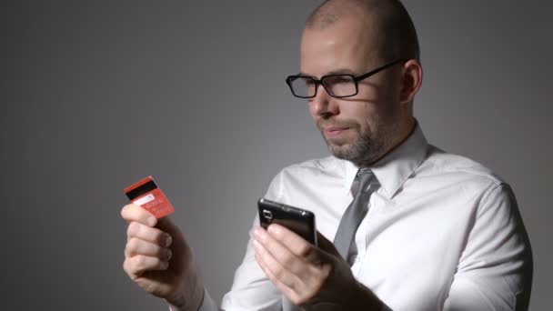 Un hombre con un hombre de negocios barba sosteniendo un teléfono móvil y las manos de la tarjeta de crédito . — Vídeos de Stock