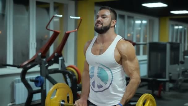 Vista redonda del hombre musculoso con barra en el gimnasio — Vídeos de Stock