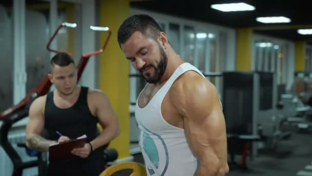 Muscular hombre levantar pesas en el gimnasio — Vídeos de Stock