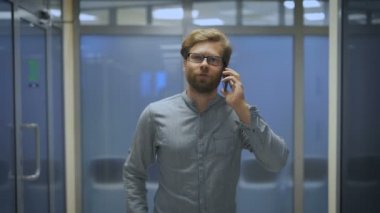 Genç adam koridorda ve telefonda konuşurken aşağı yürüyor