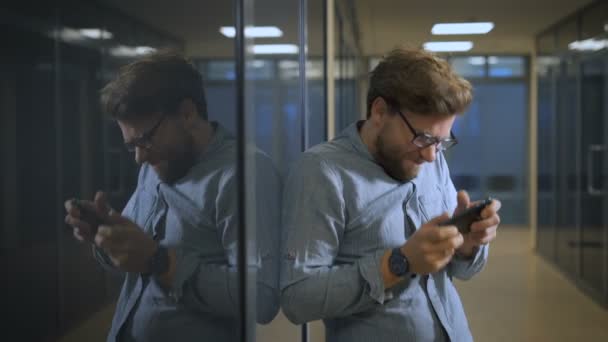 Zakenman is het spelen van spelletjes op telefoon in kantoor — Stockvideo