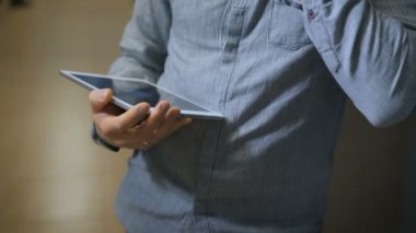 Onun ofisinde ayakta, telefon ve onay bilgi tablette konuşurken bir iş adamı