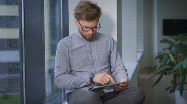 Genç işadamı pencerede oturuyor ve tarama