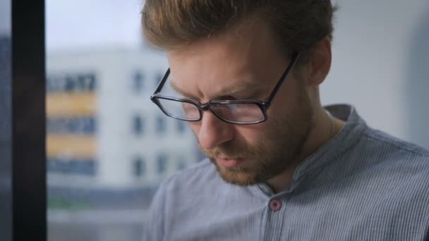 Joven hombre creativo sentado en la ventana y utilizando la tableta — Vídeos de Stock