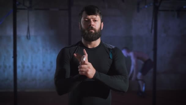 Crossfit athlete looks into the camera and flexing his hands before exercise. — Stock Video