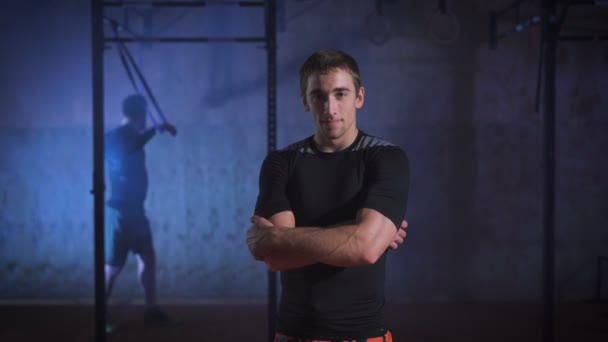 Junge Crossfit-Athletin in schwarzer Sportbekleidung blickt in die Kamera. — Stockvideo