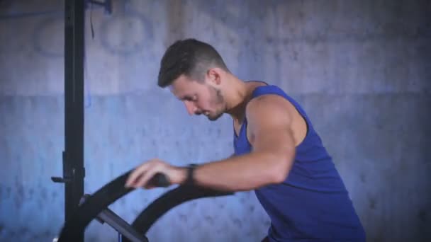 Adapter jeune homme utilisant un vélo pneumatique pour l'entraînement cardio à la salle de gym . — Video