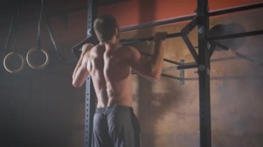 Genç kas atlet pull-up egzersizleri yapıyor.