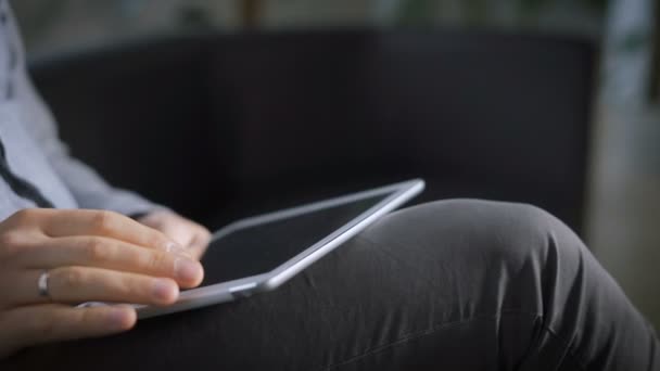 Un homme assis sur le canapé et parcourir les nouvelles sur les réseaux sociaux sur votre gadget . — Video