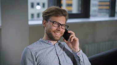 Telefonda konuşurken onun yüzünde bir gülümseme ile Resepsiyon ofiste, kanepede oturan işadamı.
