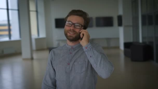 Красивый мужчина разговаривает по мобильному телефону, и он рад — стоковое видео