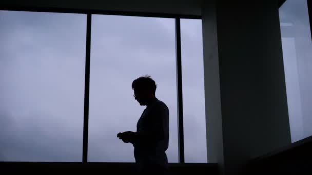 Jonge man lopen op speelt op uw mobiele telefoon in een donkere kamer. — Stockvideo