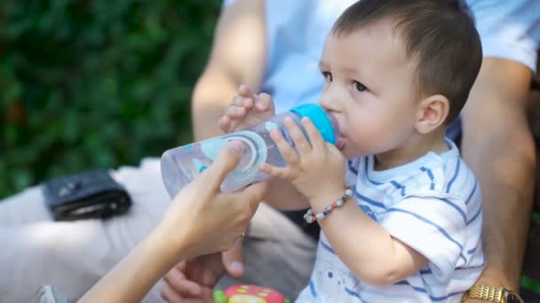 Child quenches thirst with water from a bottle. — ストック動画