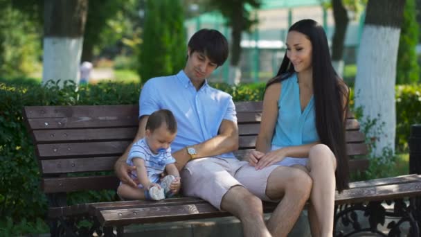 Familia feliz sentada en el banco — Vídeo de stock