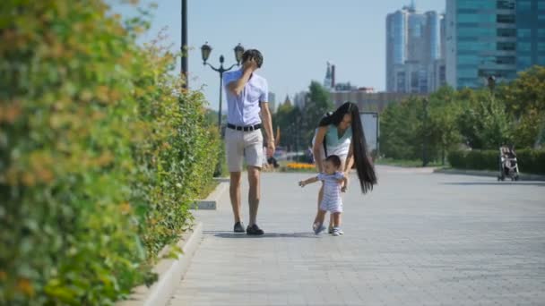 Young family walking along the alley. — Stockvideo