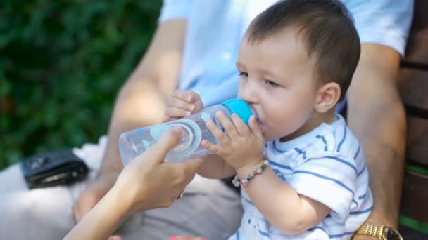 Child quenches thirst with water from a bottle. — Stock video