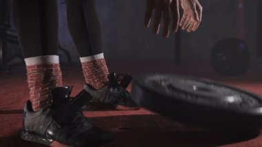 Disk ağırlık bırakarak eğitim elbiseli kas sporcunun yakın çekim.