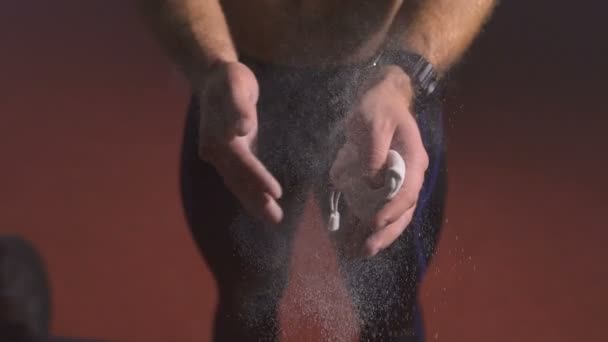 Strong man applying magnesia powder on his palms and preparing to do exercises. — Stock video