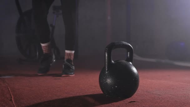 Primer plano del hombre fuerte en traje de entrenamiento que va a la Kettlebell y tomarlo con ambas manos y levantarlo en cámara lenta . — Vídeo de stock