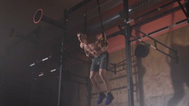 Spor Yüzüklerin jimnastik salonu kas-up egzersizleri yapıyor iyi durumda genç adam.