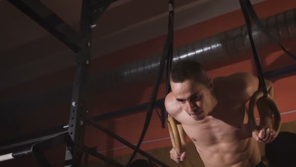 Close up of the shirtless athlete doing muscle-up exercise on the sport rings. — ストック動画